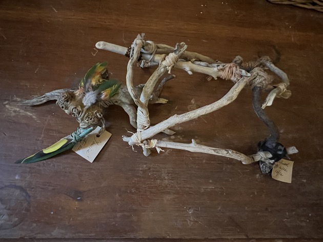 Amanda Farquharson “Yowie” and “Wurley" 2022 Driftwood, lorikeet feathers, twine 10cm x 20 cm. $220 and $220.